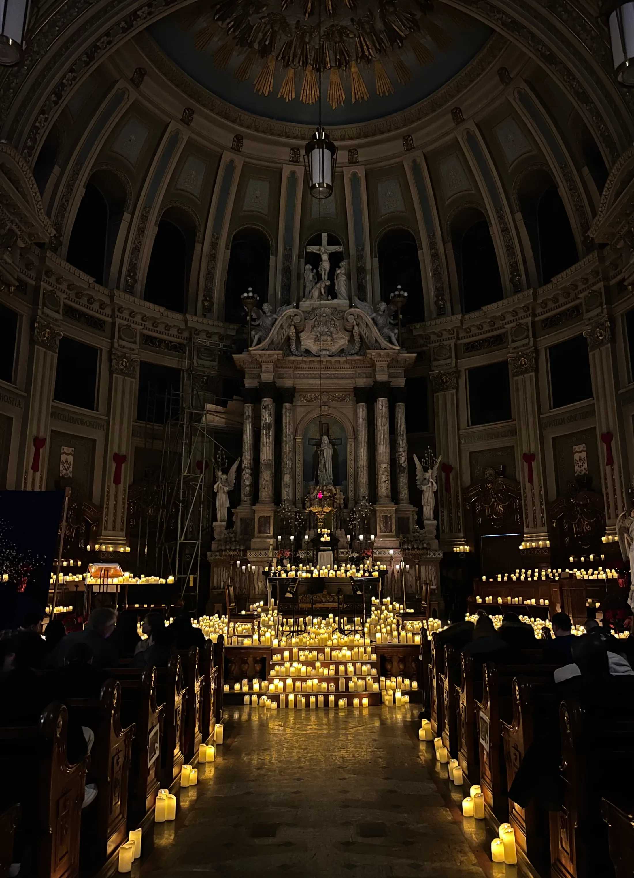 The altar of a church lit by hundreds of small candles on the steps and along the pews