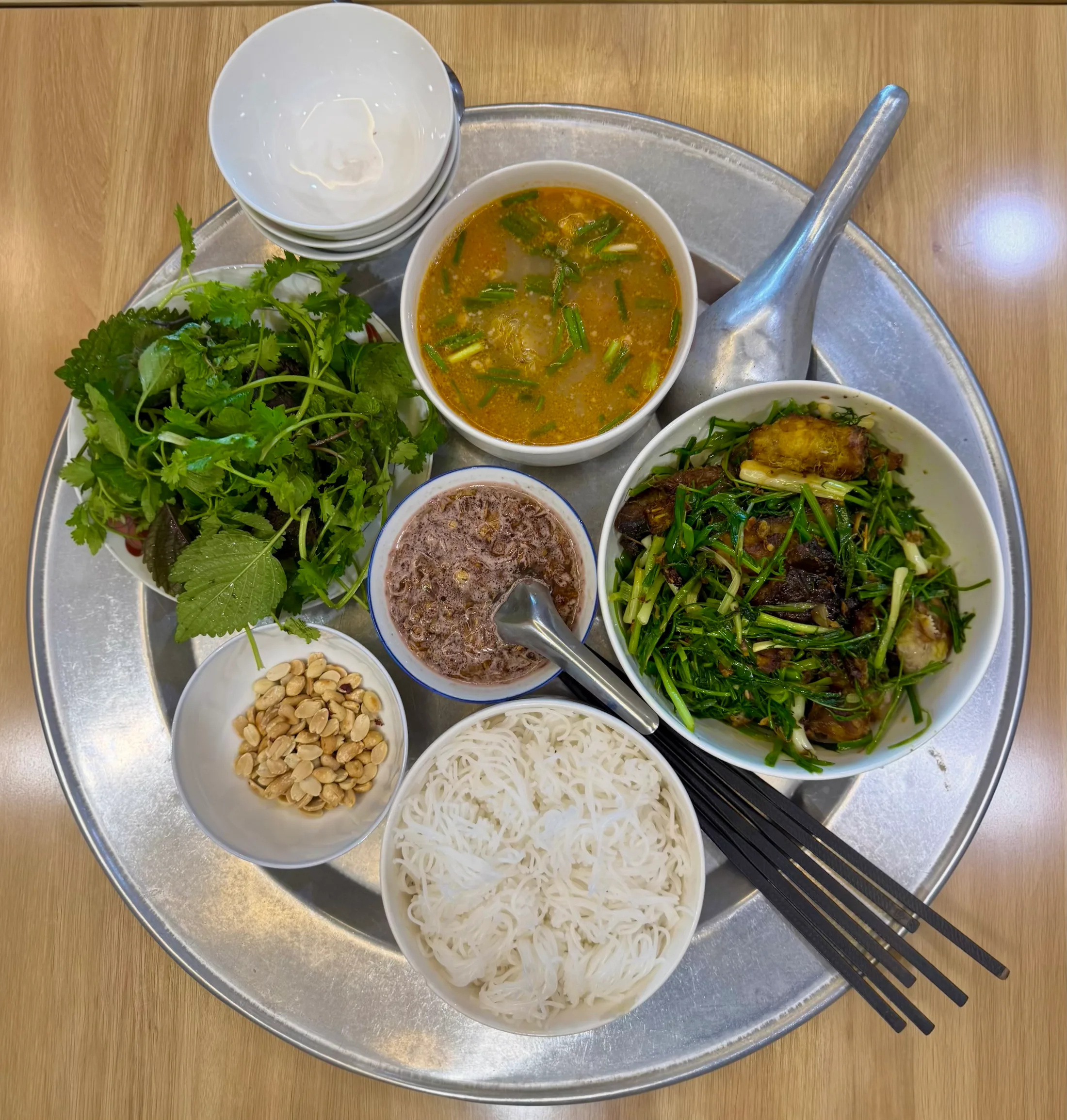A tray of chả cá — fried fish with dill and spring onion — with bún, peanuts, herbs, mắm tôm and a bowl of broth