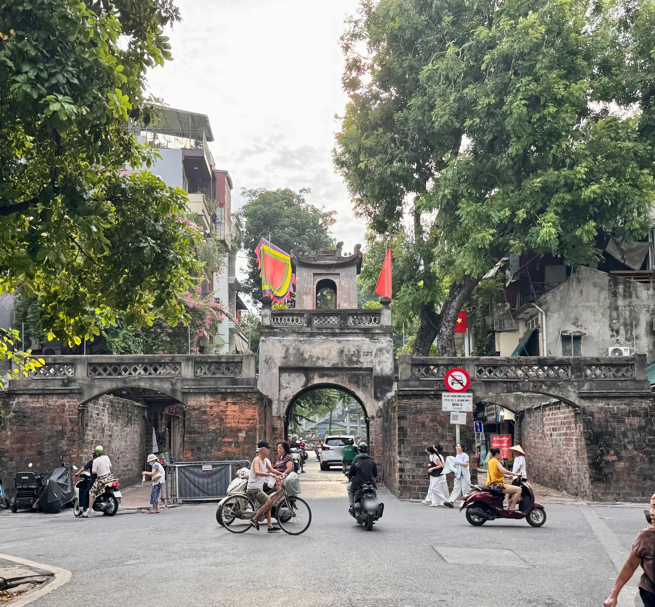 The Ô Quan Chưởng gate in Hanoi’s old quarter, mopeds and bicycles passing through it